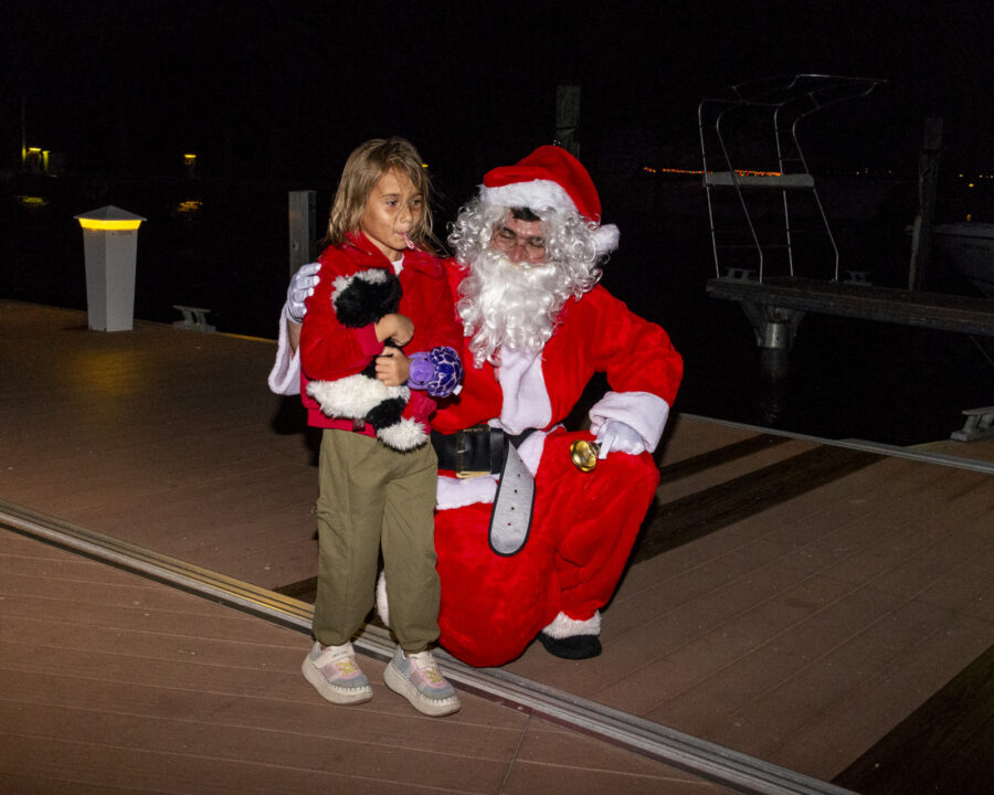 a little girl standing next to a santa clause