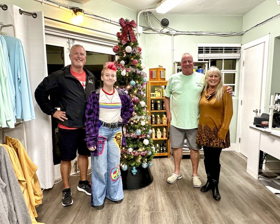 a group of people standing next to a christmas tree