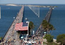 a crowd of people walking across a bridge next to the ocean