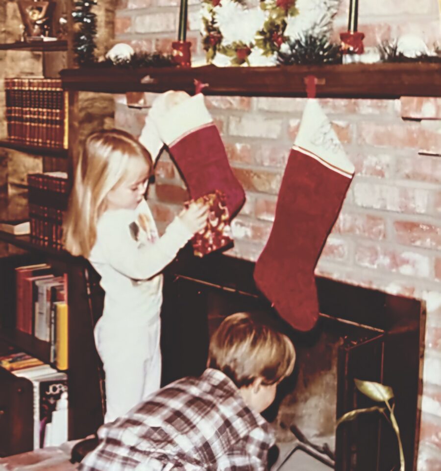 a couple of kids hanging stockings on a fireplace