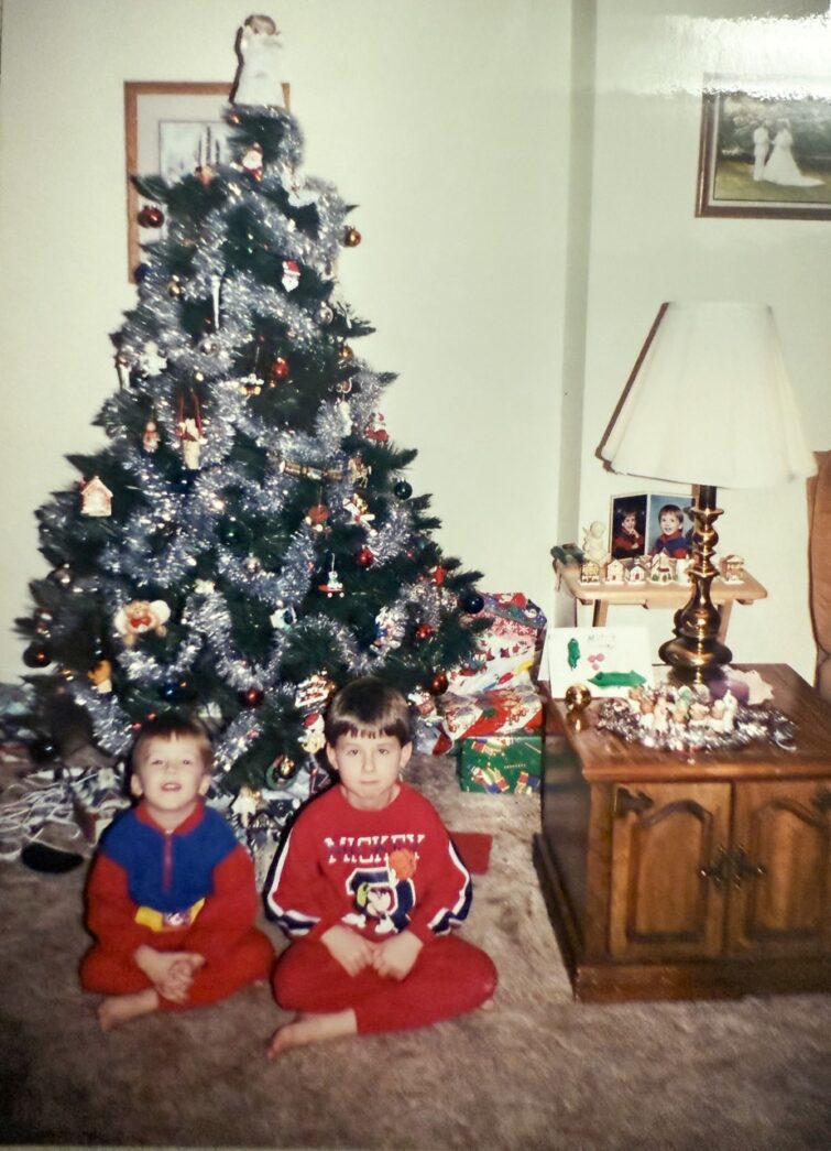 two young boys sitting in front of a christmas tree