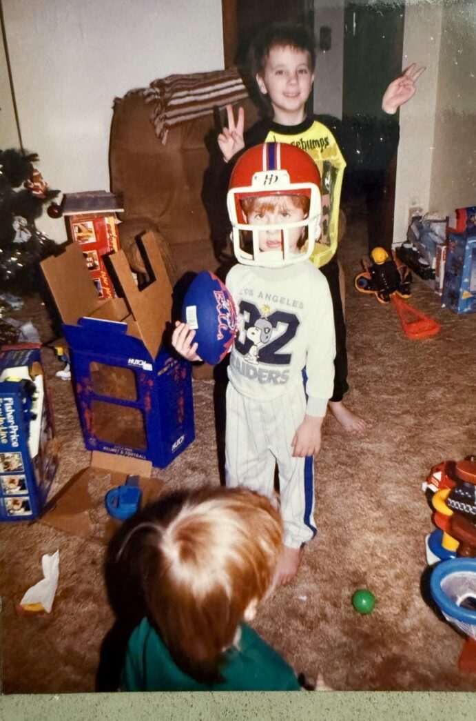 a young boy holding a football helmet in a living room