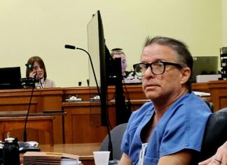 a man sitting at a table in a courtroom