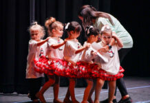 a group of young girls standing on top of a stage