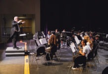 a conductor and orchestra performing on a stage