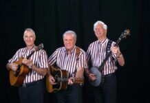 a group of men standing next to each other holding guitars