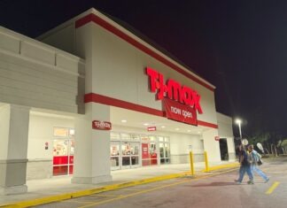 a store front at night with people walking by