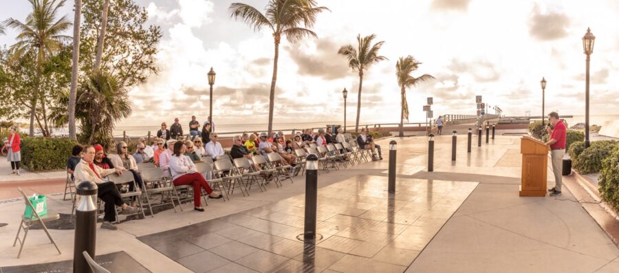 a crowd of people sitting on top of a sidewalk