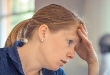 a woman sitting at a desk with her hand on her head