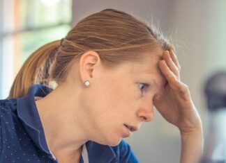 a woman sitting at a desk with her hand on her head