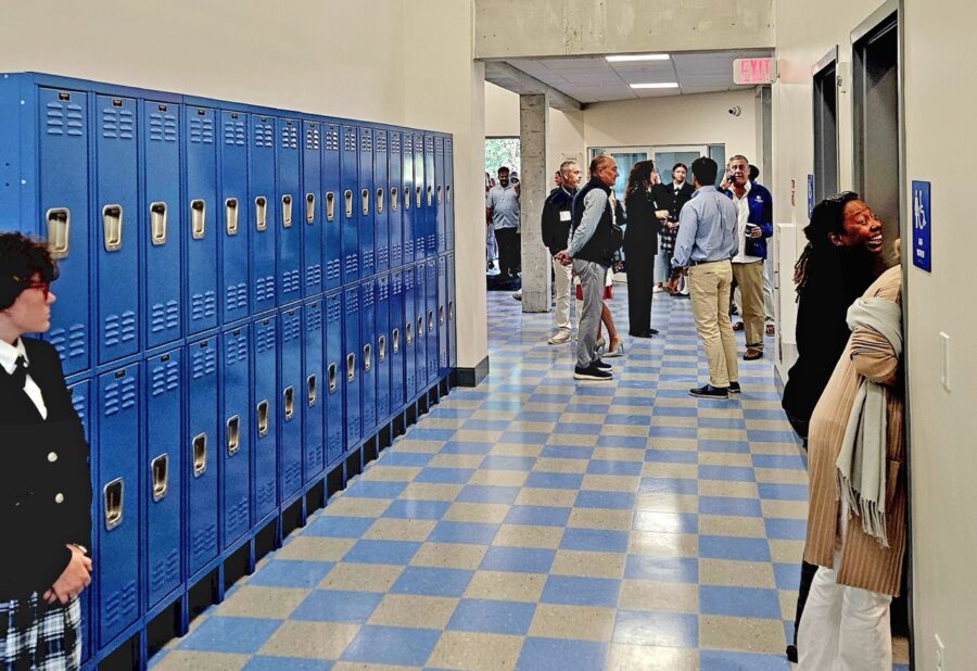 a group of people standing in a hallway next to lockers