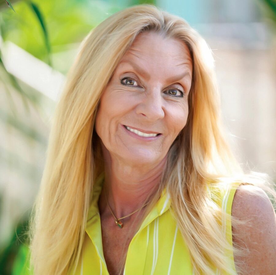 a woman with long blonde hair wearing a yellow shirt