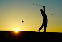 a silhouette of a person playing golf at sunset