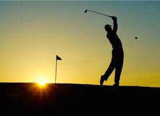 a silhouette of a person playing golf at sunset