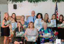 a group of people holding up paintings in front of a table