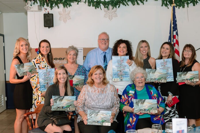 a group of people holding up paintings in front of a table