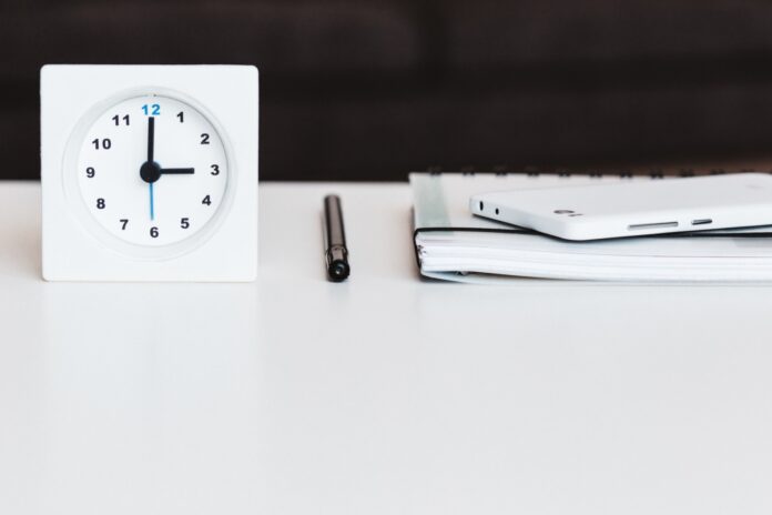 a white clock sitting on top of a white table