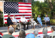 a group of people sitting in front of an american flag