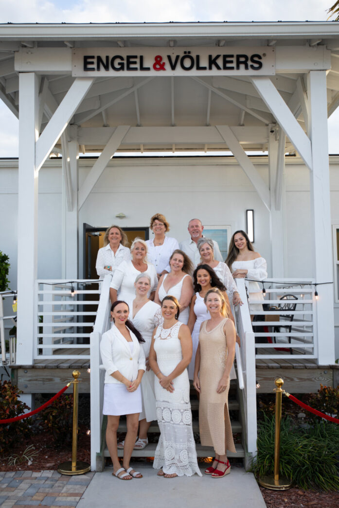 a group of women standing in front of a white building