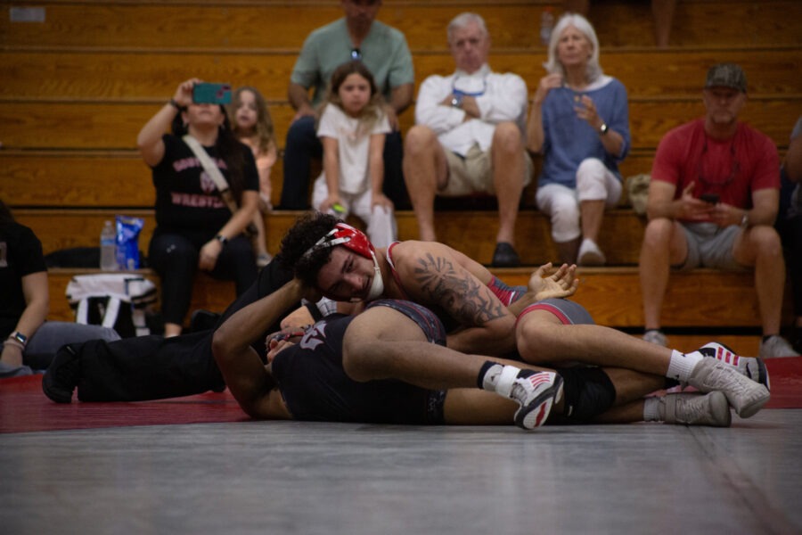 a wrestling match in progress with a crowd watching