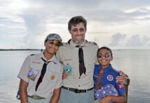 a man standing next to two boys on a boat