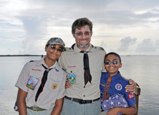 a man standing next to two boys on a boat