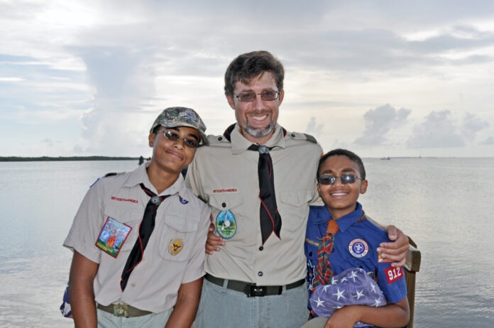 a man standing next to two boys on a boat