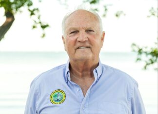 a man in a blue shirt standing in front of a tree