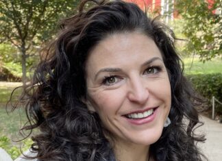 a woman with curly hair smiling at the camera