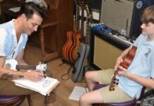 a man sitting next to a boy with a guitar