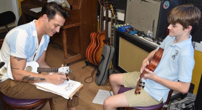 a man sitting next to a boy with a guitar