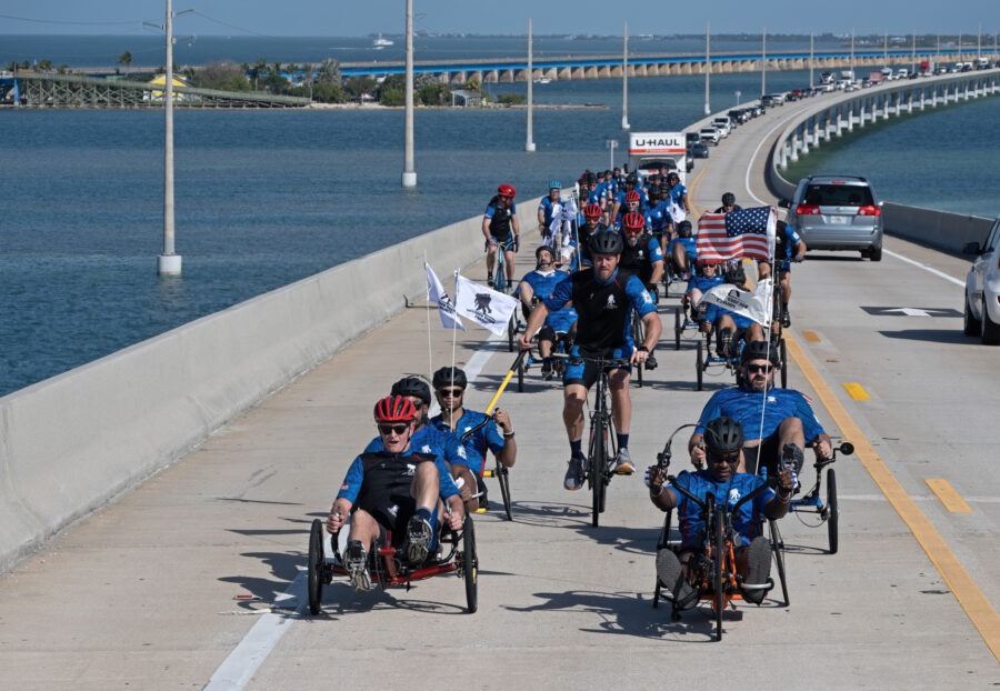 a group of bicyclists riding on a bridge