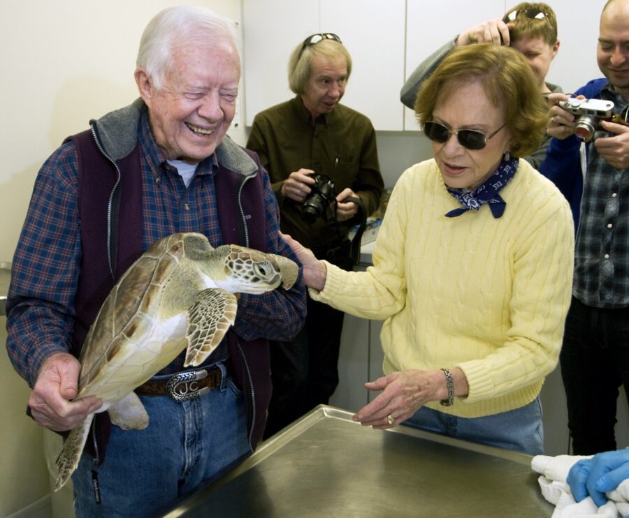 a woman holding a turtle in front of a group of people