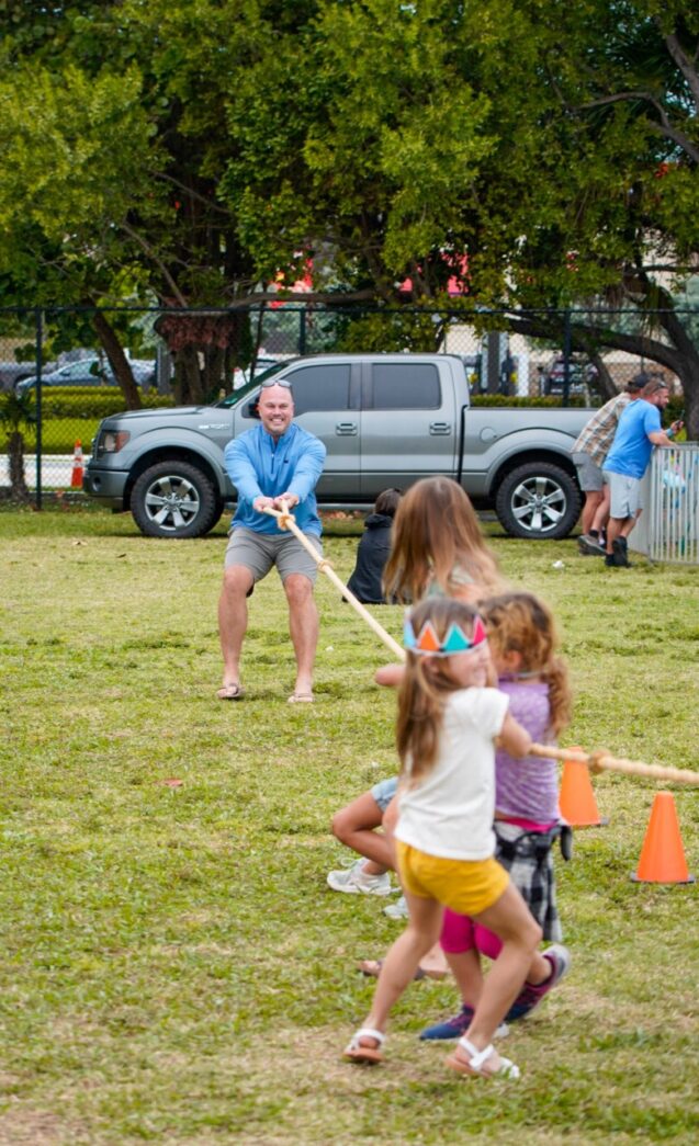 a group of children playing tug of war in a park