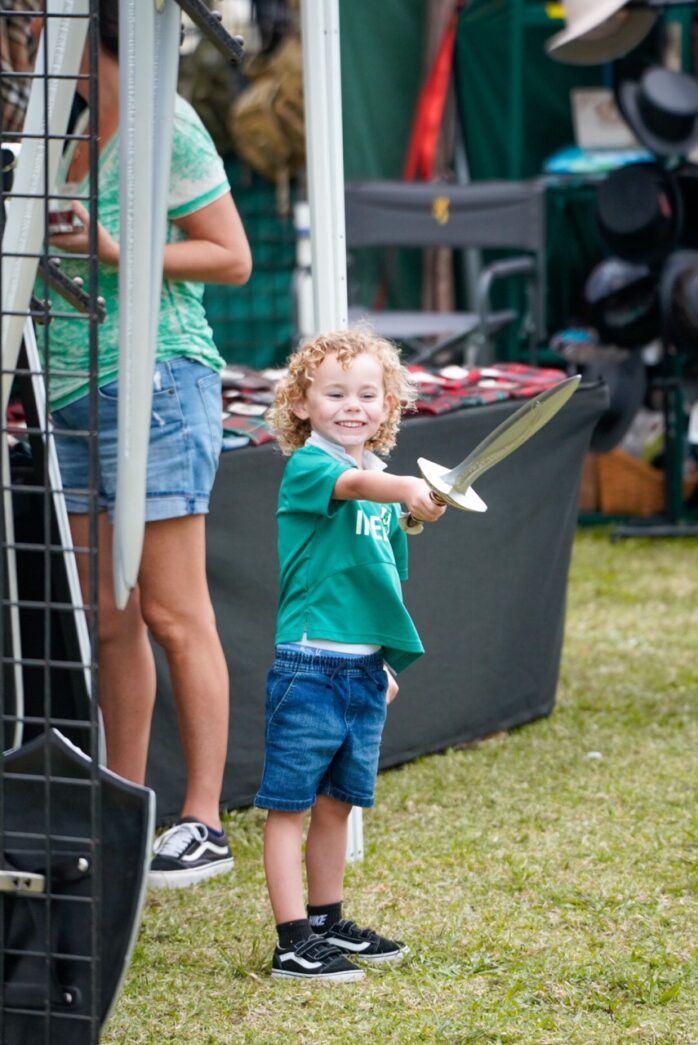 a little boy holding a white frisbee on top of a field