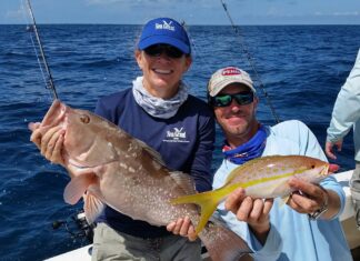 a couple of men on a boat holding a fish