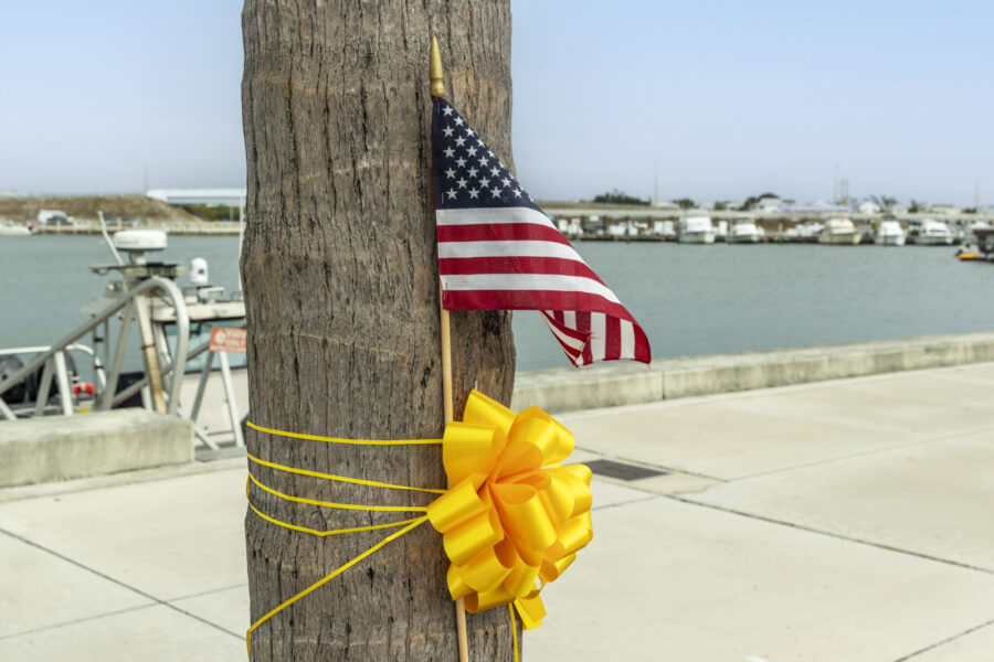 a pole with a flag and a yellow bow tied to it