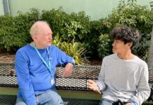 two men sitting on a bench talking to each other