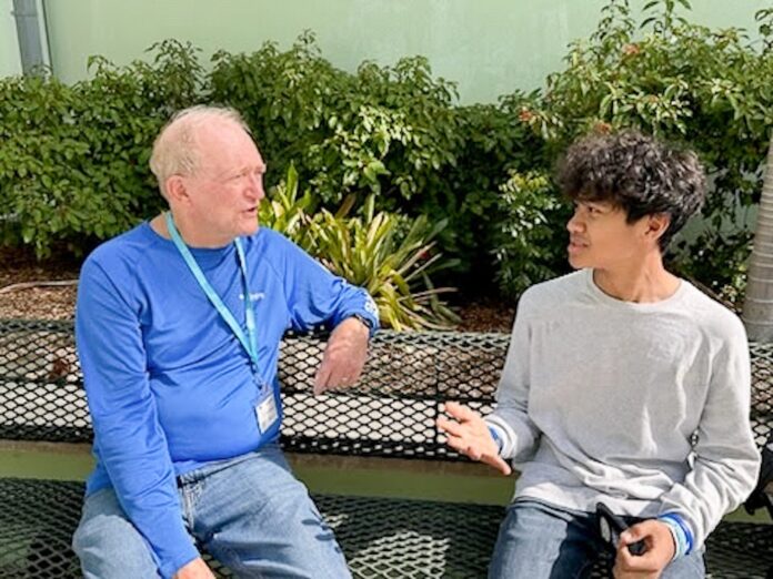 two men sitting on a bench talking to each other