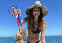 a woman in a bikini holding a fish