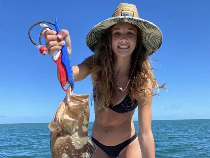 a woman in a bikini holding a fish