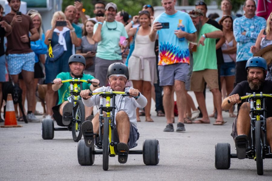 a group of people riding tricycles down a street