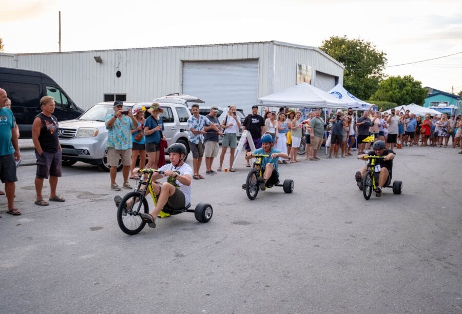 a group of people watching children ride tricycles