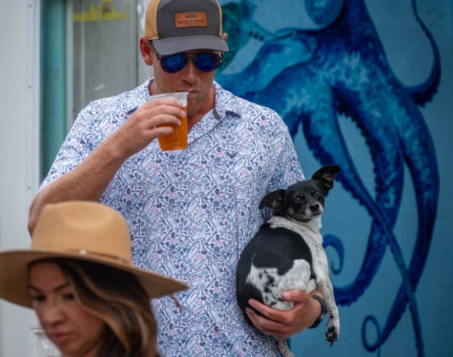 a man holding a dog in his arms while wearing a hat