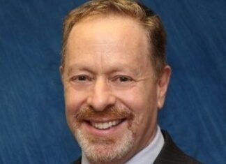 a man in a suit and tie smiling at the camera