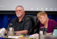 a man and woman sitting at a table in front of a projector screen