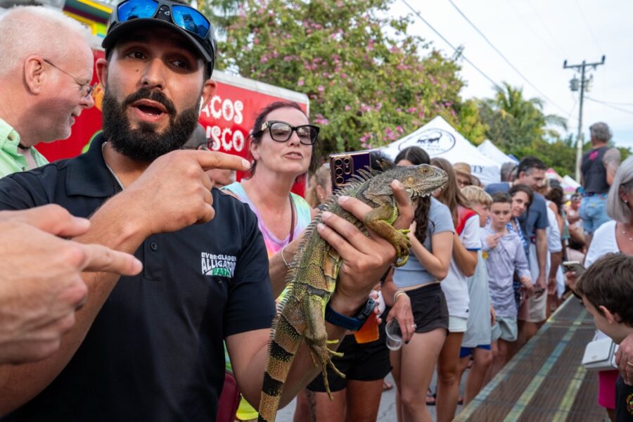 a man holding a lizard in front of a crowd of people