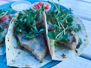 a blue plate topped with three tacos covered in toppings