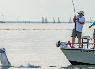 two men standing on a boat with a fish in the water