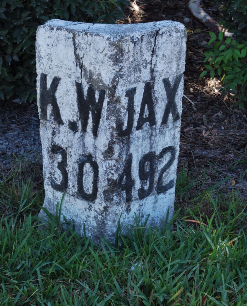 a cement block sitting in the grass near a bush